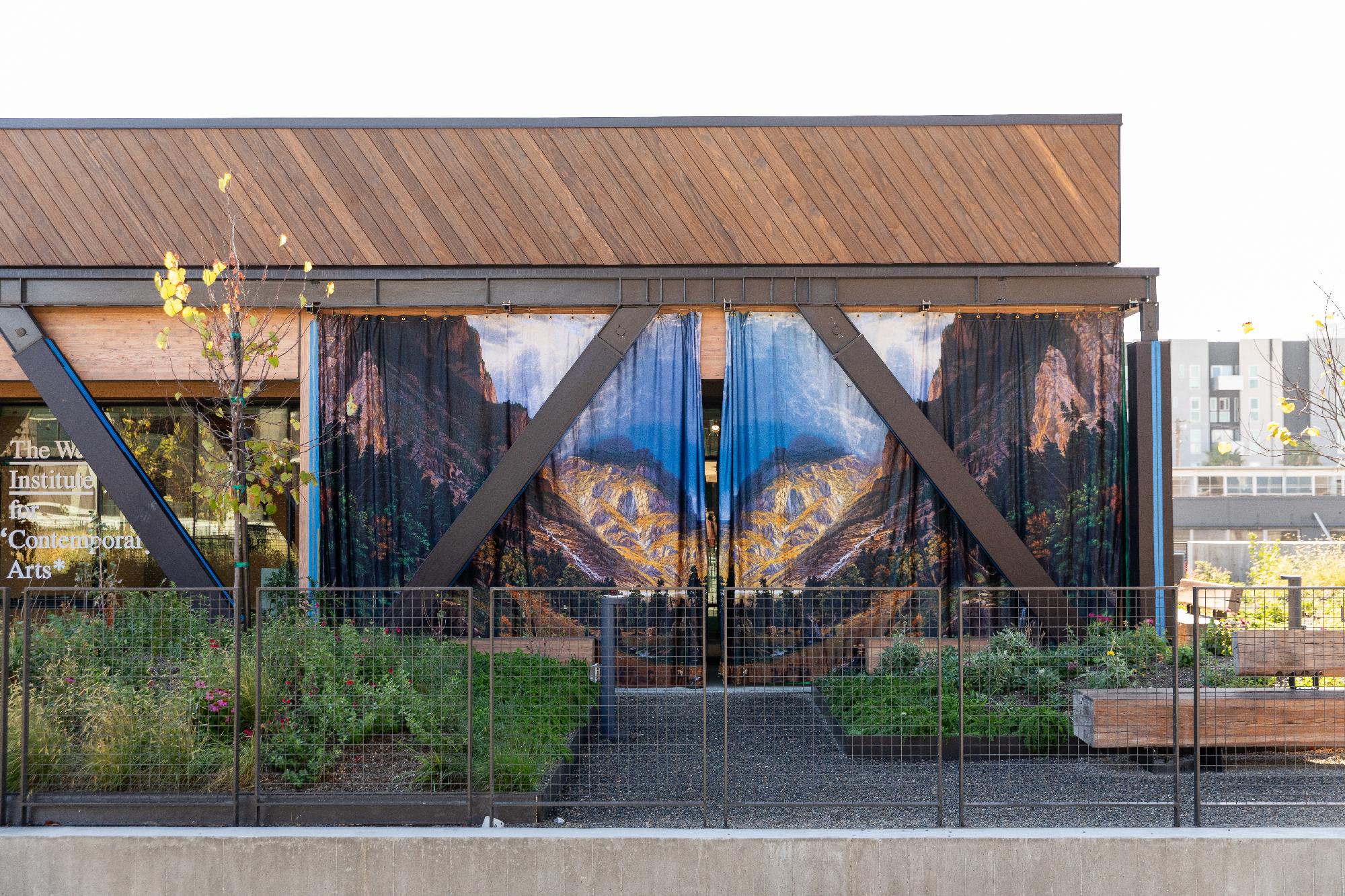 printed curtains with landscape images hung outside low-slung builidng