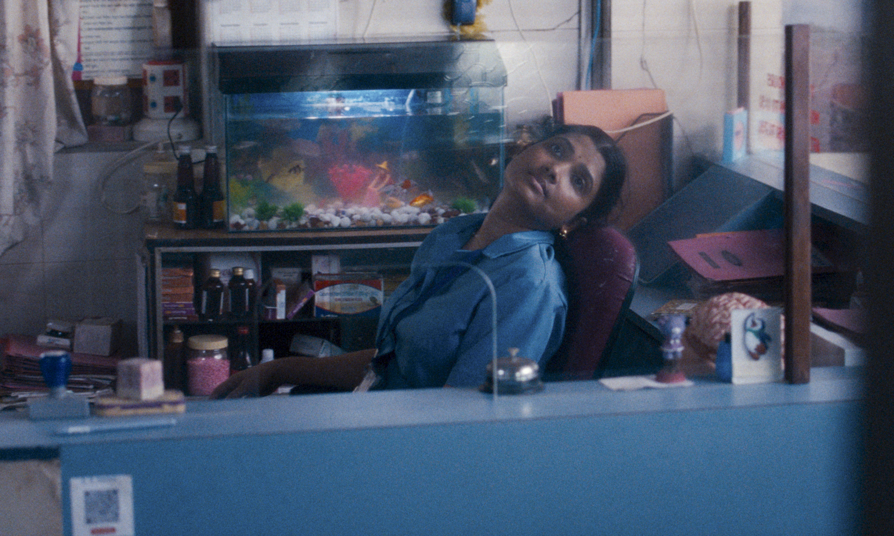 woman in blue uniform leans back in chair at work