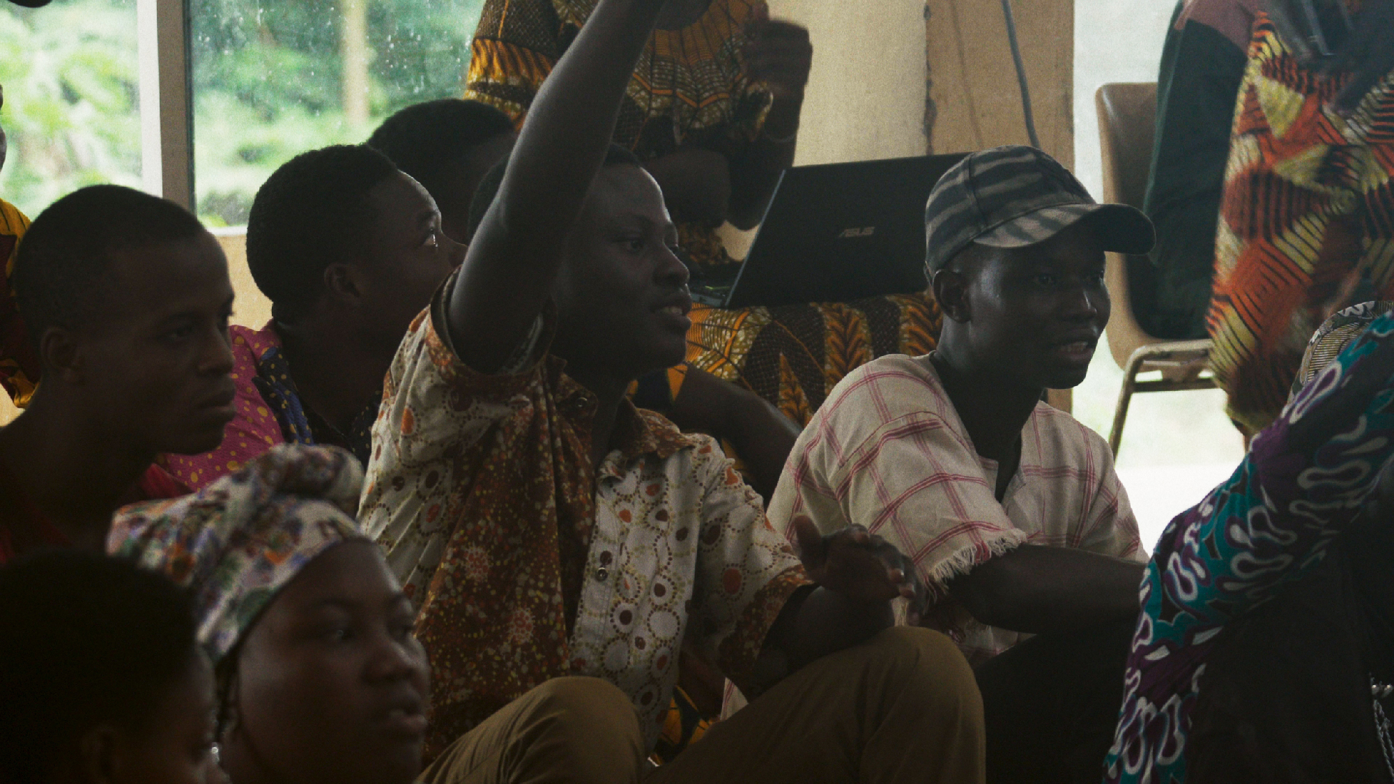 man raises hand in seated group