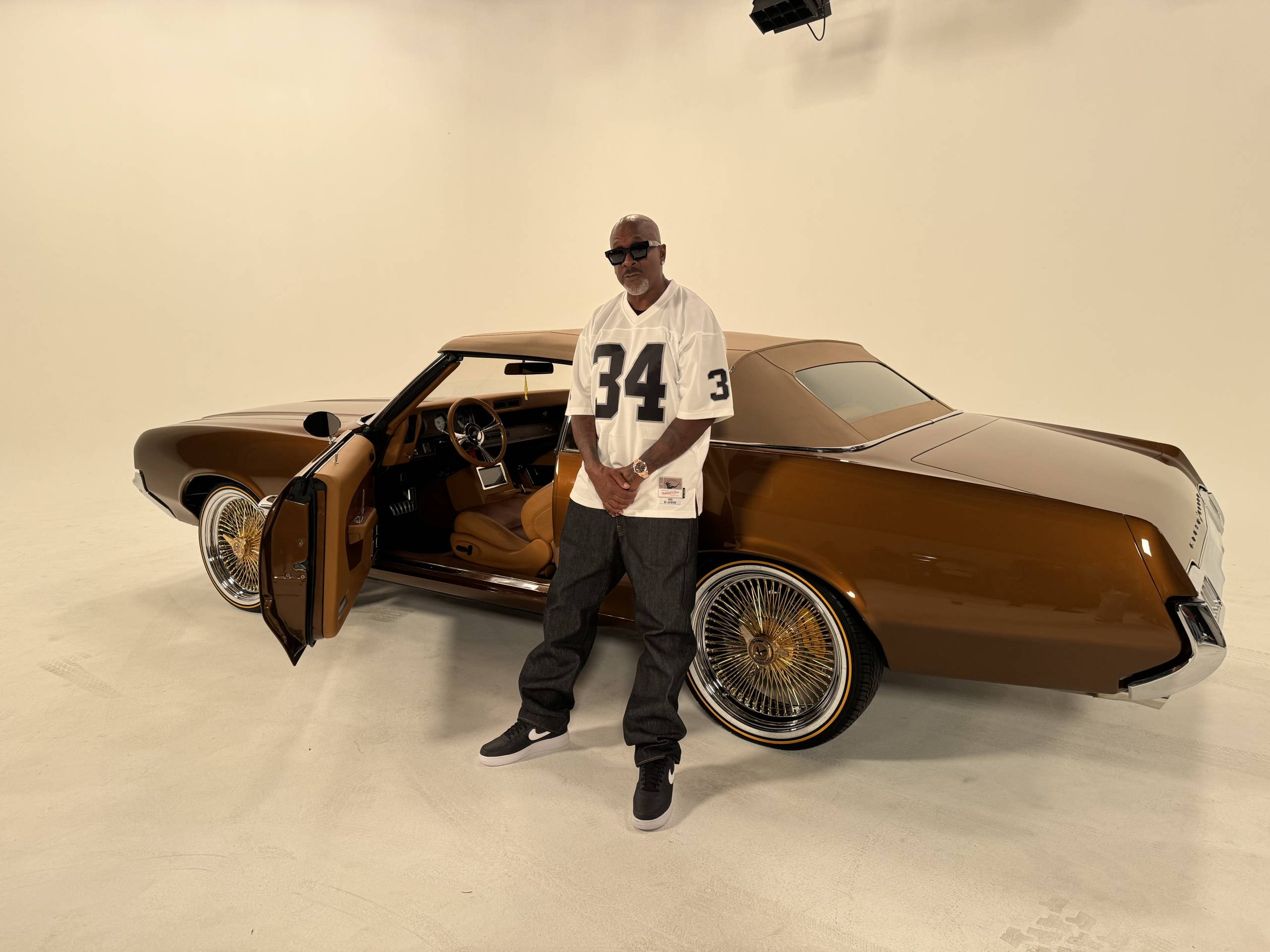 Rapper Richie Rich poses in a Raiders Bo Jackson jersey, while standing in front of his Cutlass Oldsmobile.