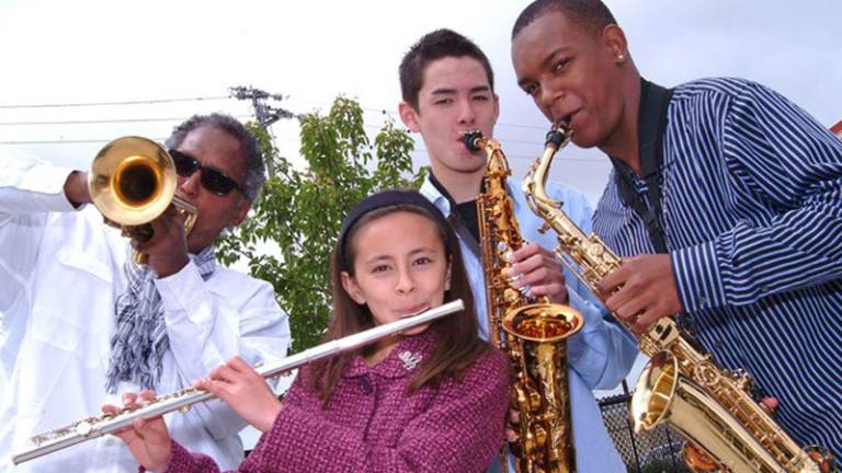 Oaktown Jazz Workshops’ late Founding Director Khalil Shaheed poses next to a handful of students, as they all hold an assortment of instruments, circa 2008.