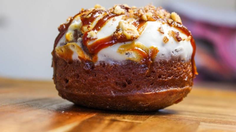 A pumpkin cake doughnut topped with caramel, pecans and cream cheese frosting