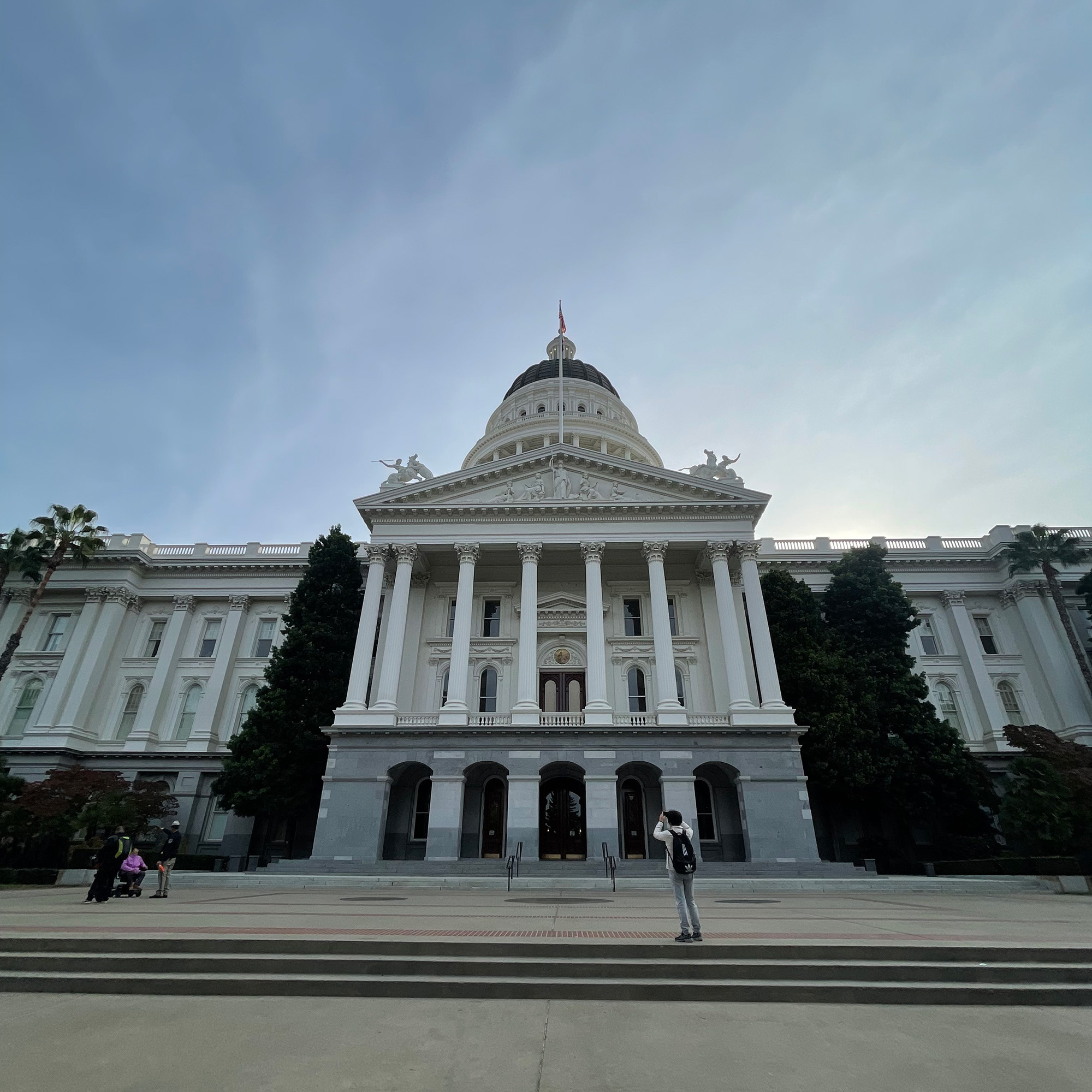 A tourist takes a photo from the the steps of the California State Capitol building.