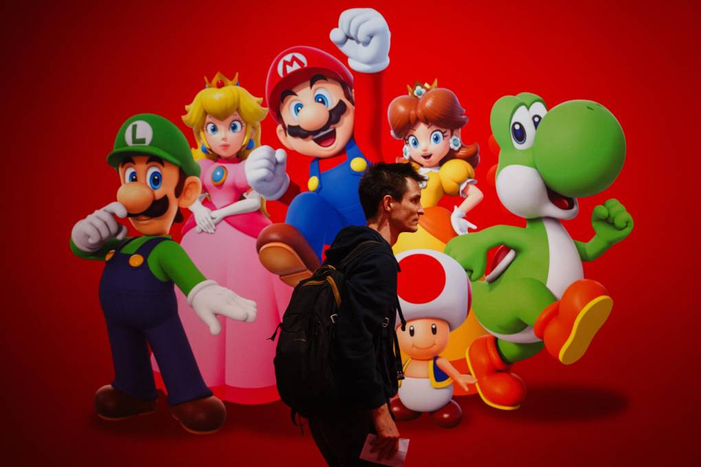 A man walks past a Super Mario video game poster, featuring multiple characters.