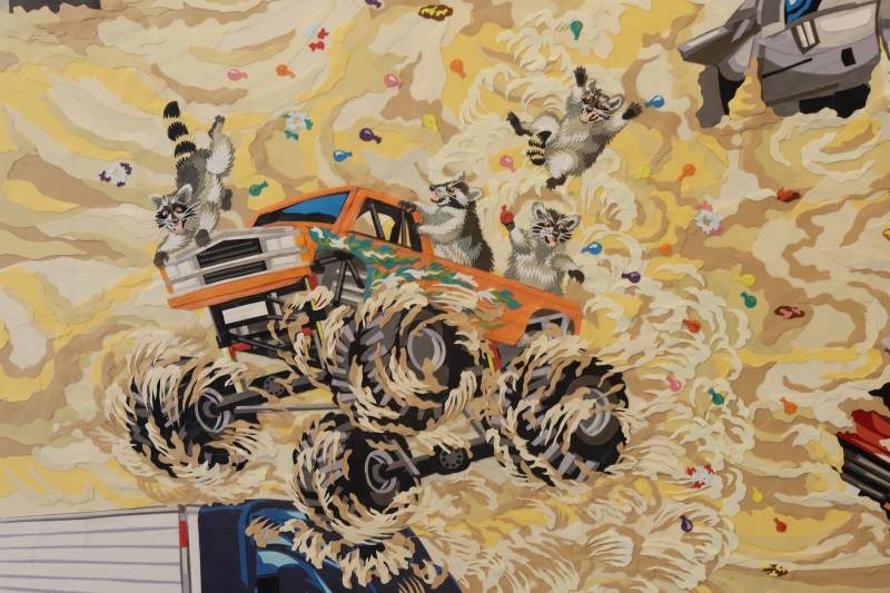 cut paper artwork showing raccoon riding monster truck