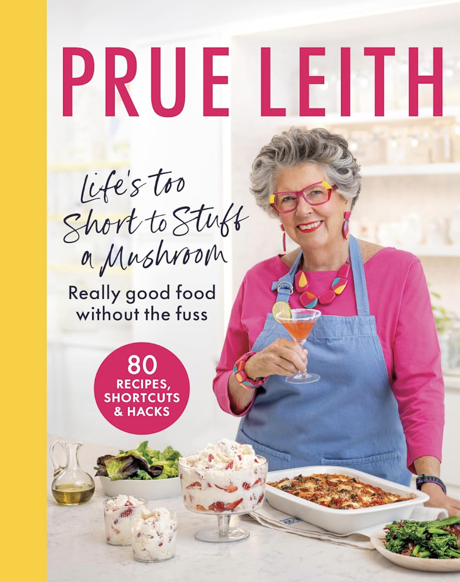 A book cover featuring a smiling, senior woman wearing an apron, pink sweater and holding a martini glass. Plates of food sit on the counter in front of her.