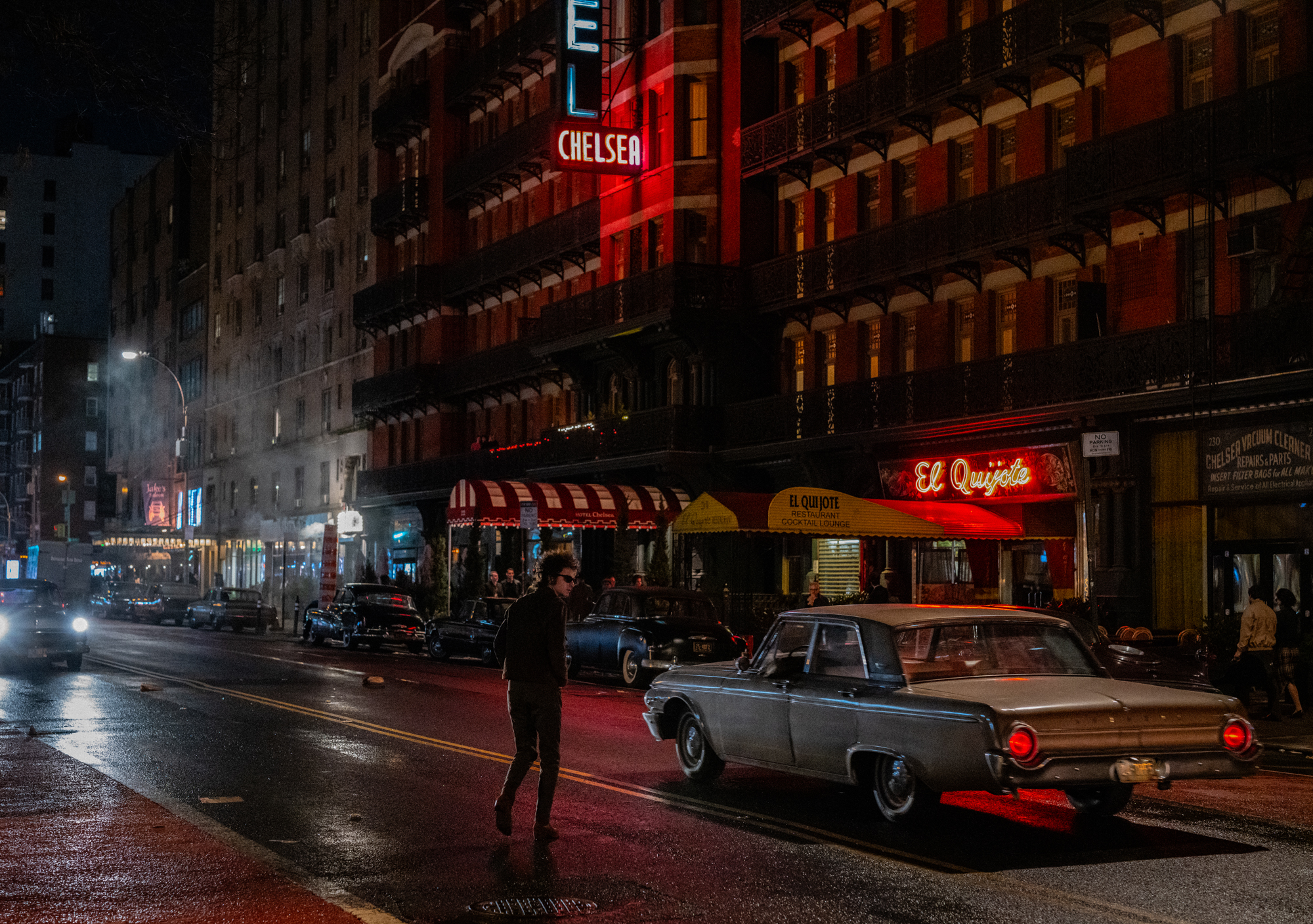 figure in dark clothes crosses street in front of chelsea hotel