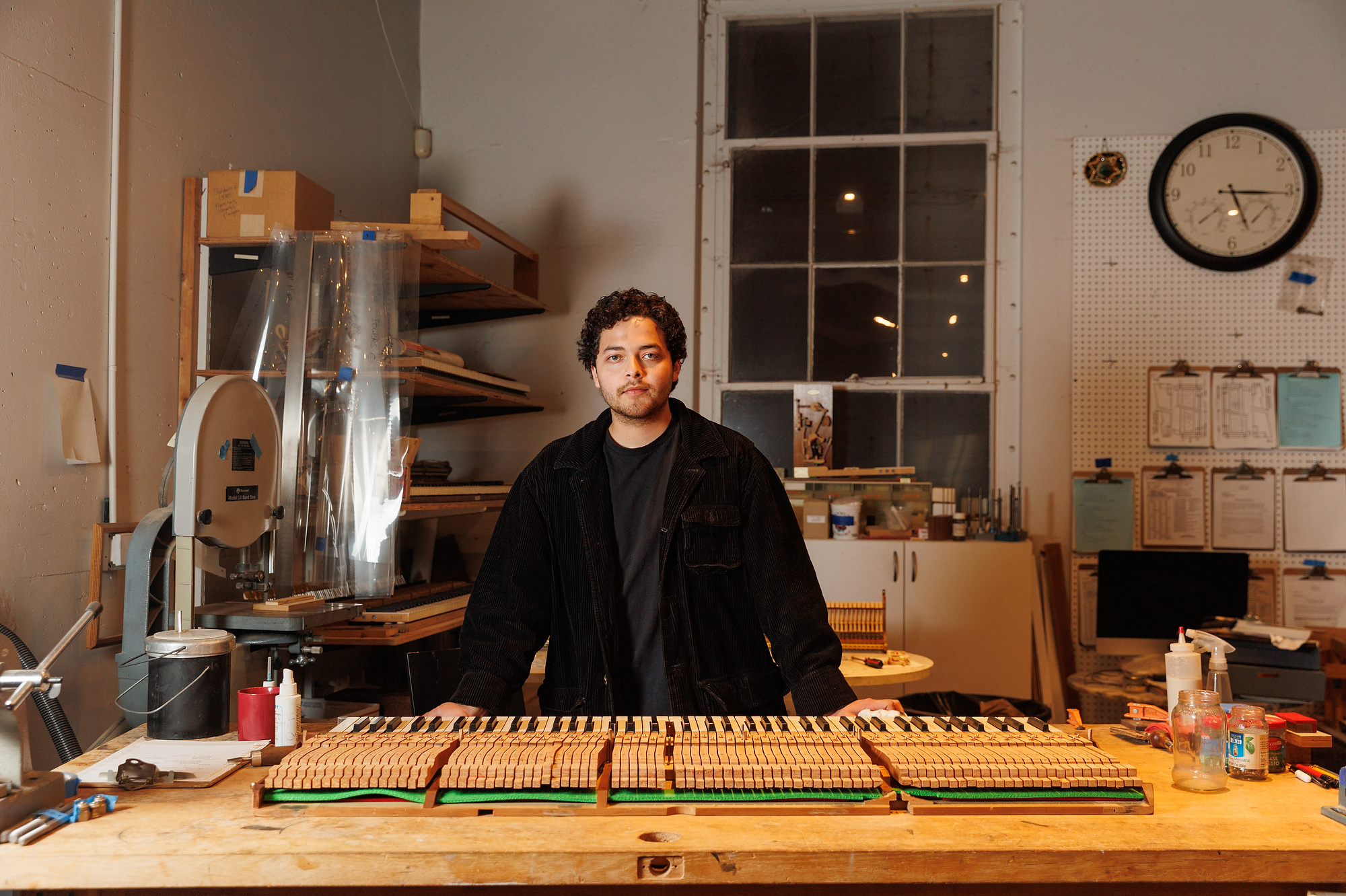 a young man wit brown hair sits behind a keyboard