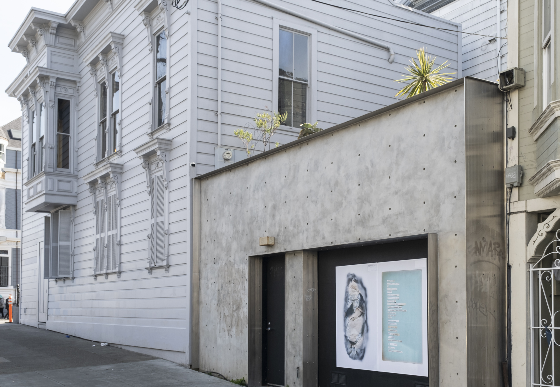 concrete-faced garage next to light gray Victorian house on corner