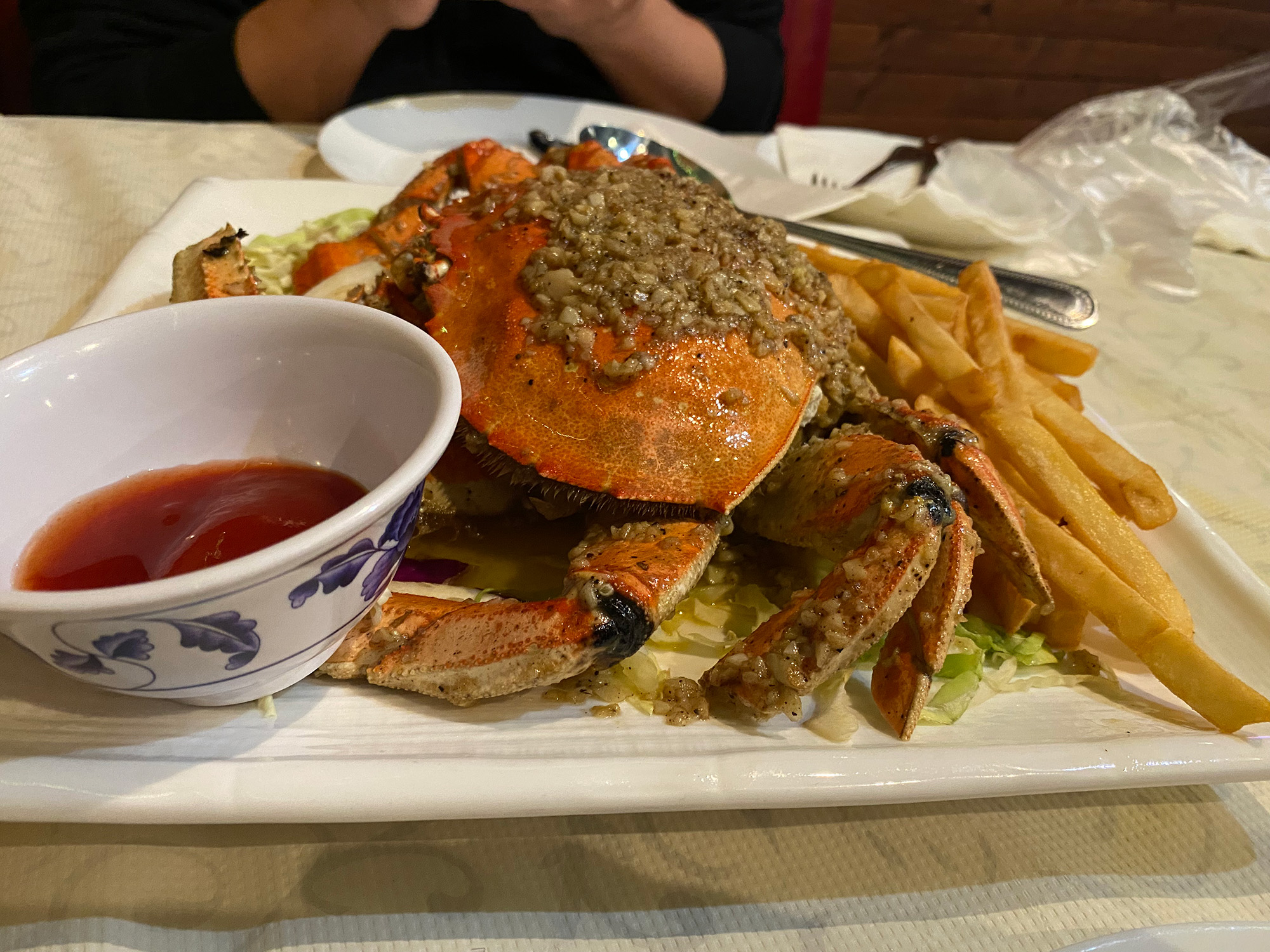 A whole Dungeness crab served on a plate over a bed of French fries.