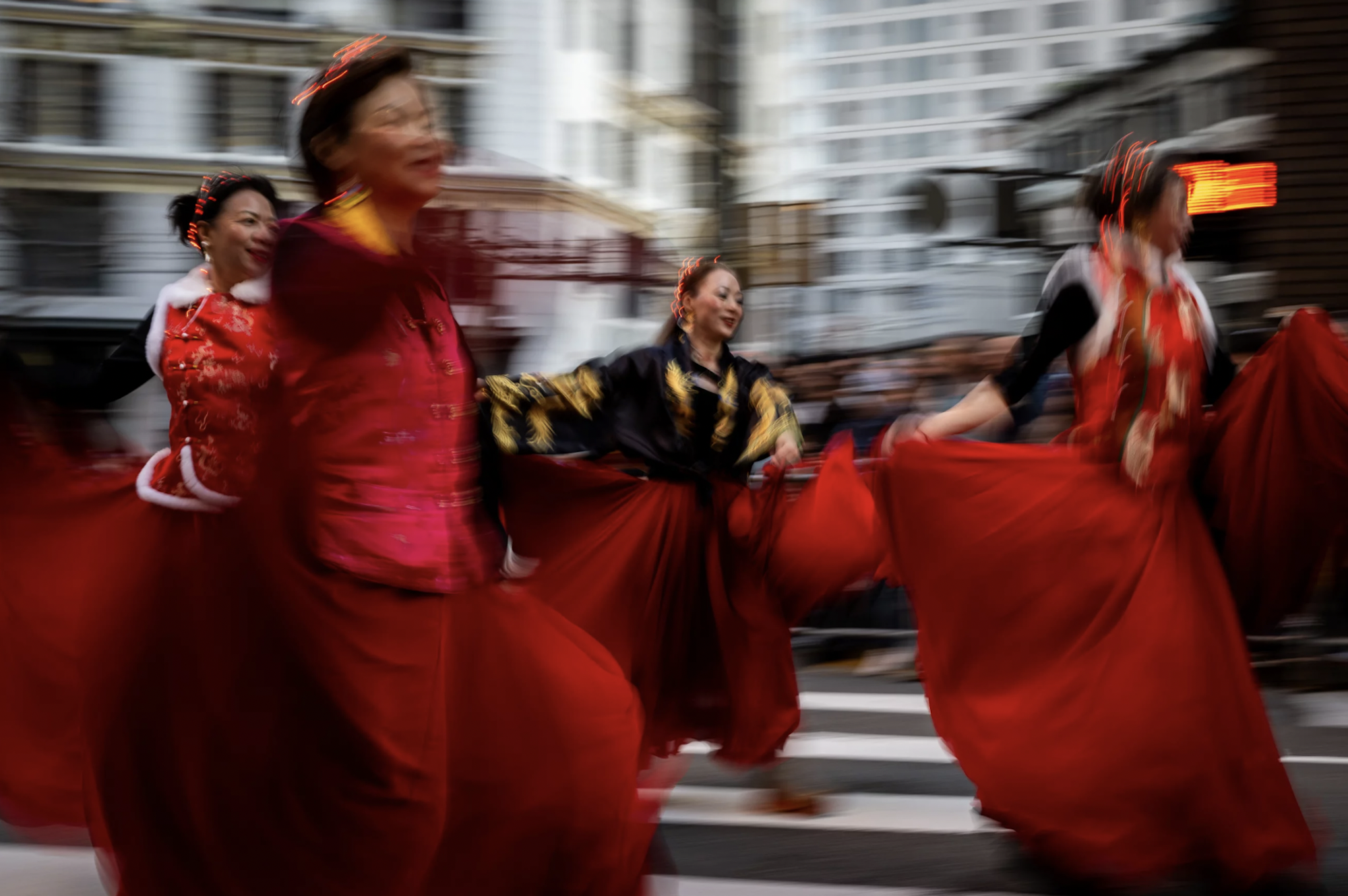 Four dancers in motion, spin their skirts as they dance through a downtown intersection.