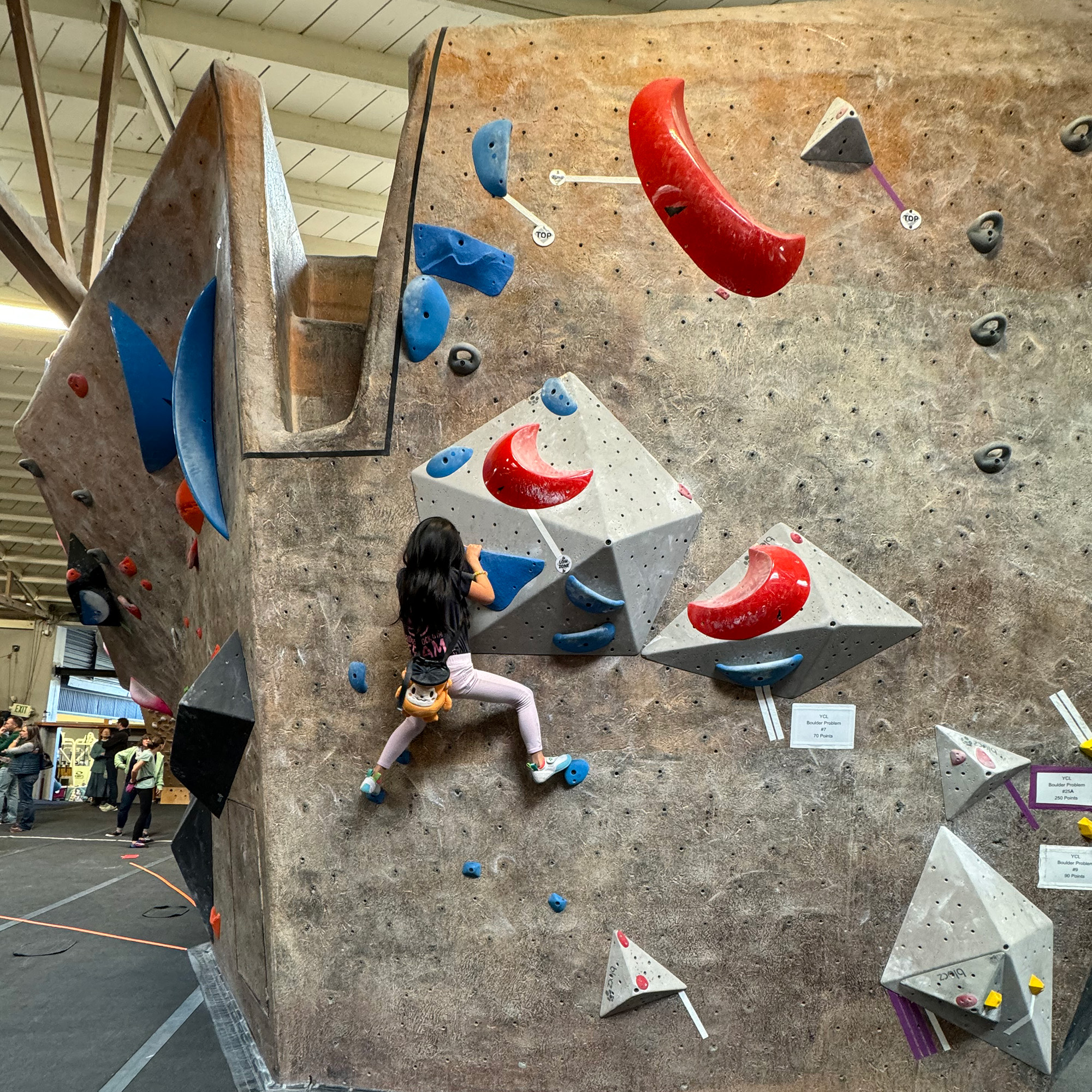 Young girl climbs a bouldering wall.