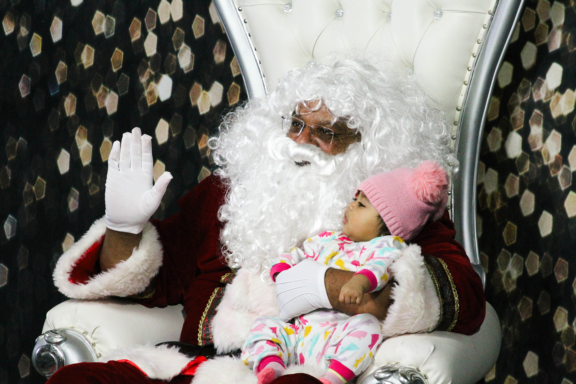 Santa Claus poses for a photo with a baby.