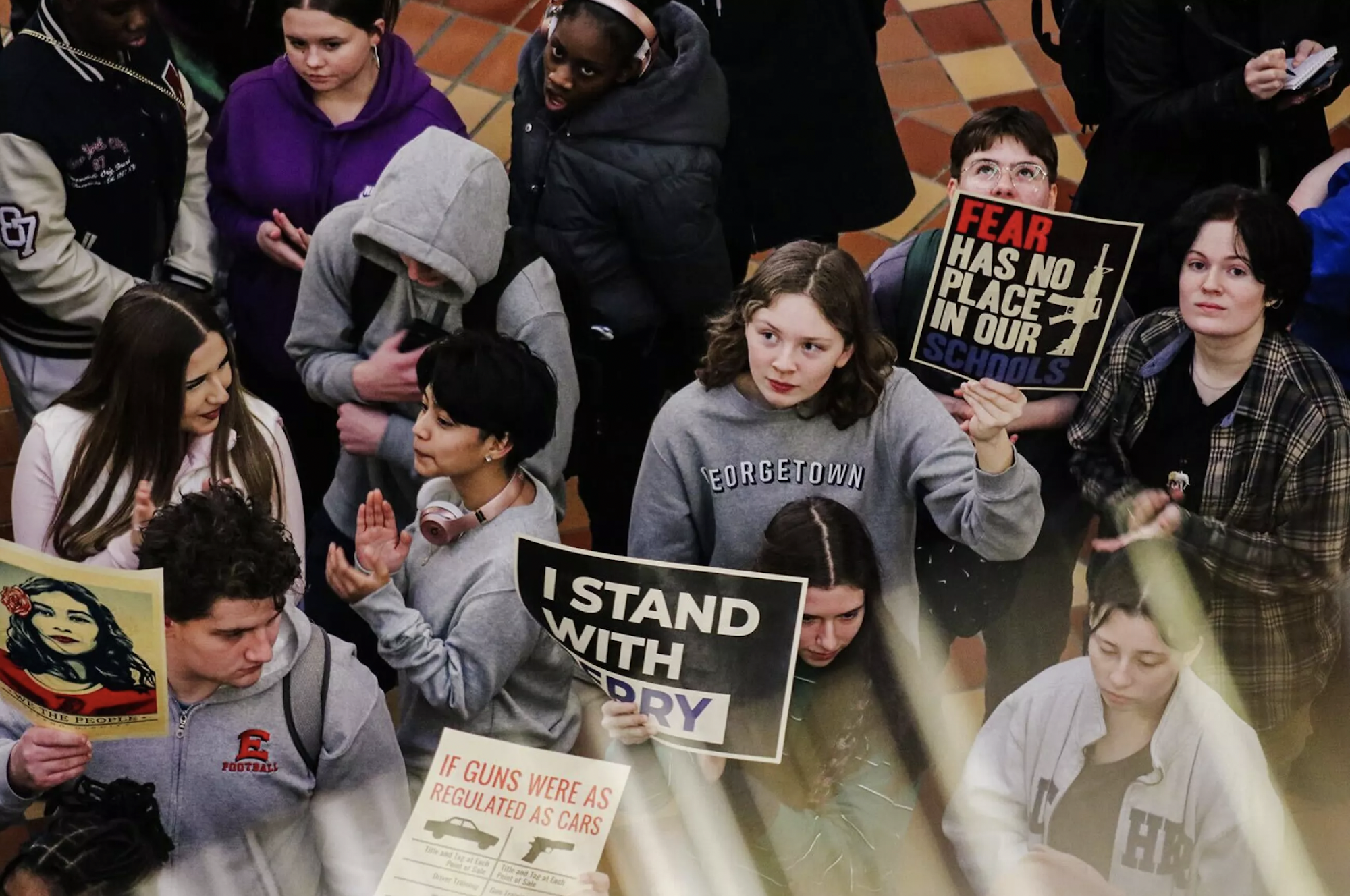 Young people of various races stand close together, many of them holding protest signs relating to gun control.