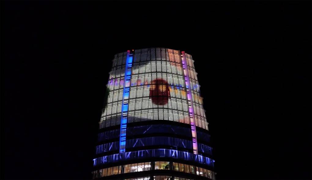 Image of the Salesforce Tower lit up with a color geometric light display.