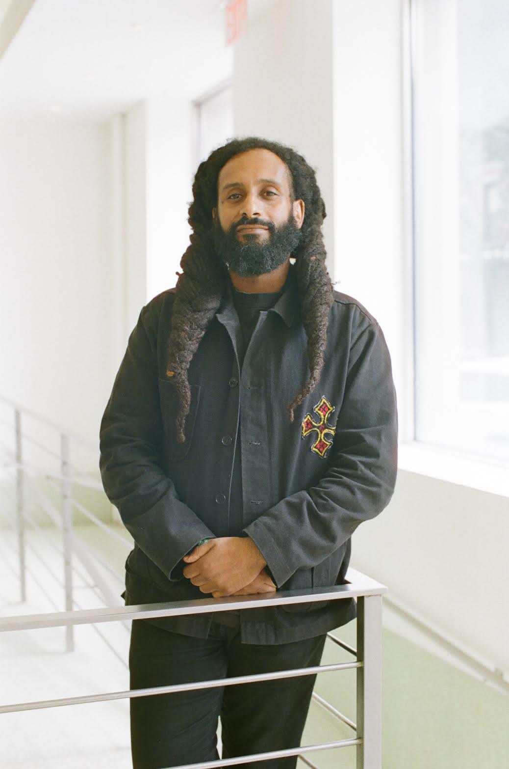 Daniel Aderaw Yeshiwas, manager of Cafe Colucci, poses for a photo in a black jacket in front of a white background.