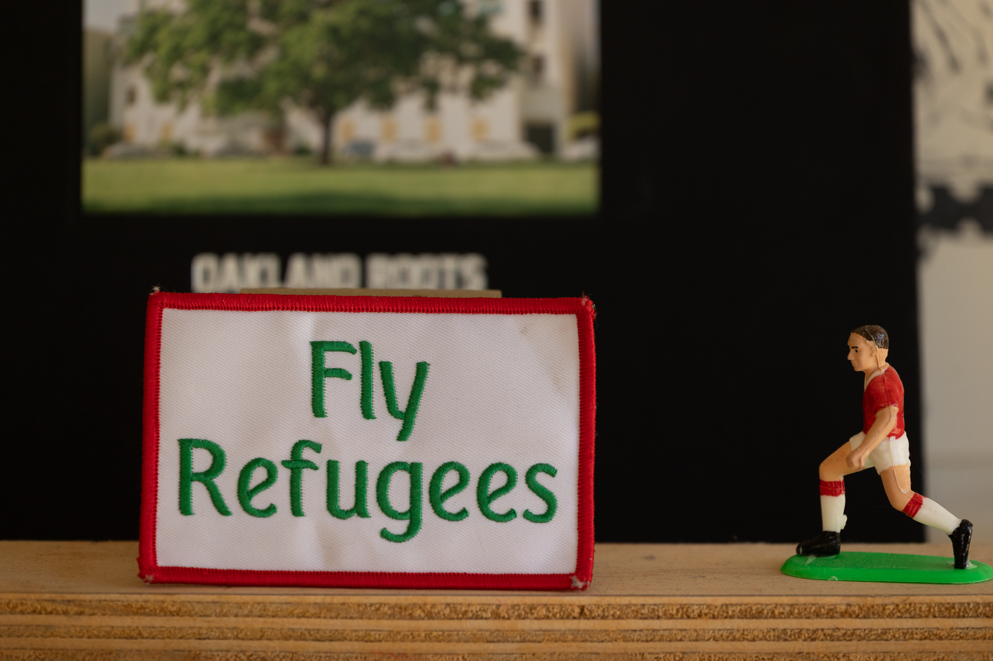 'fly refugees' patch next to figurine of soccer player