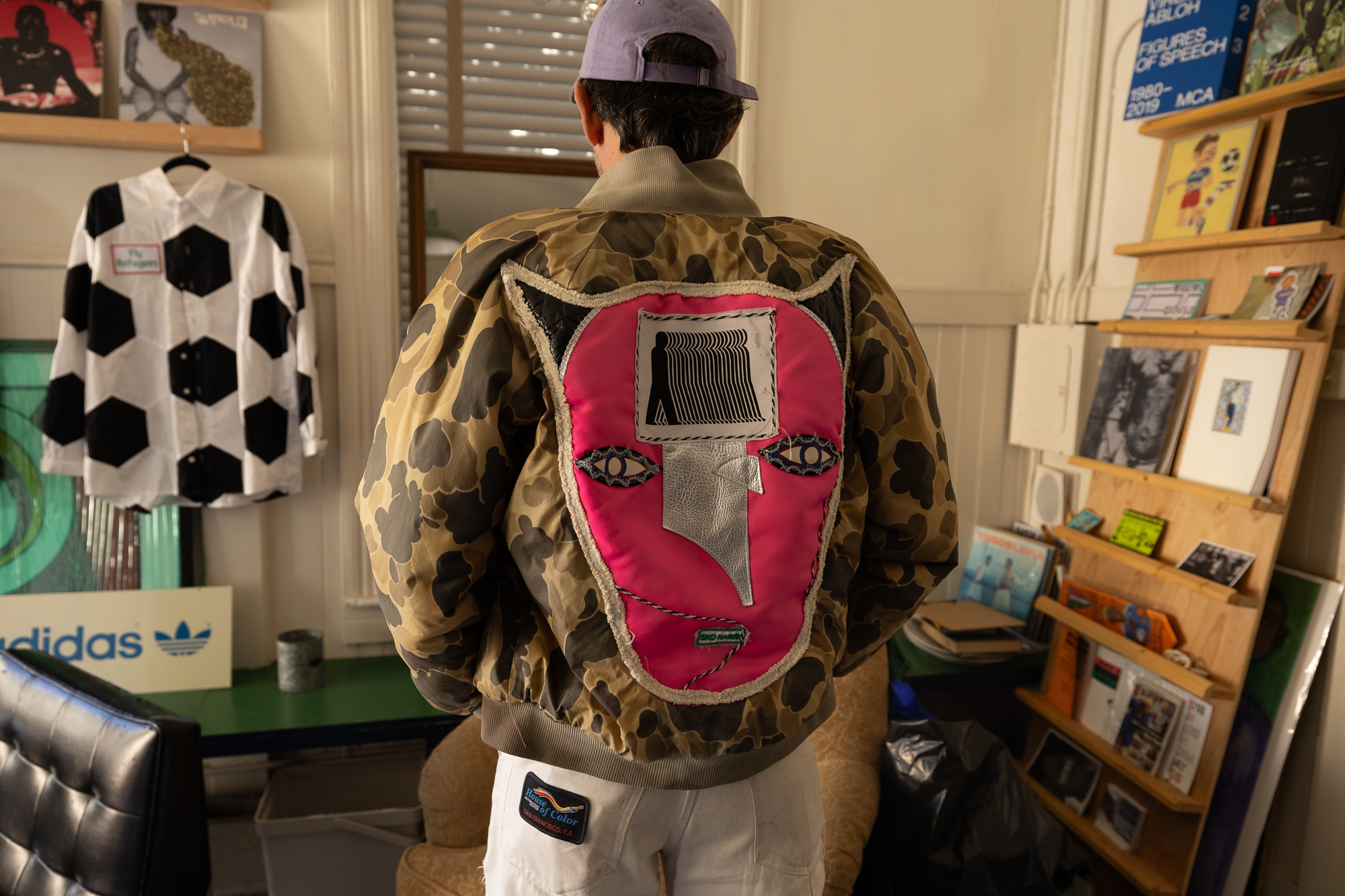 man with camo jacket and cat head in embroidered textiles on back