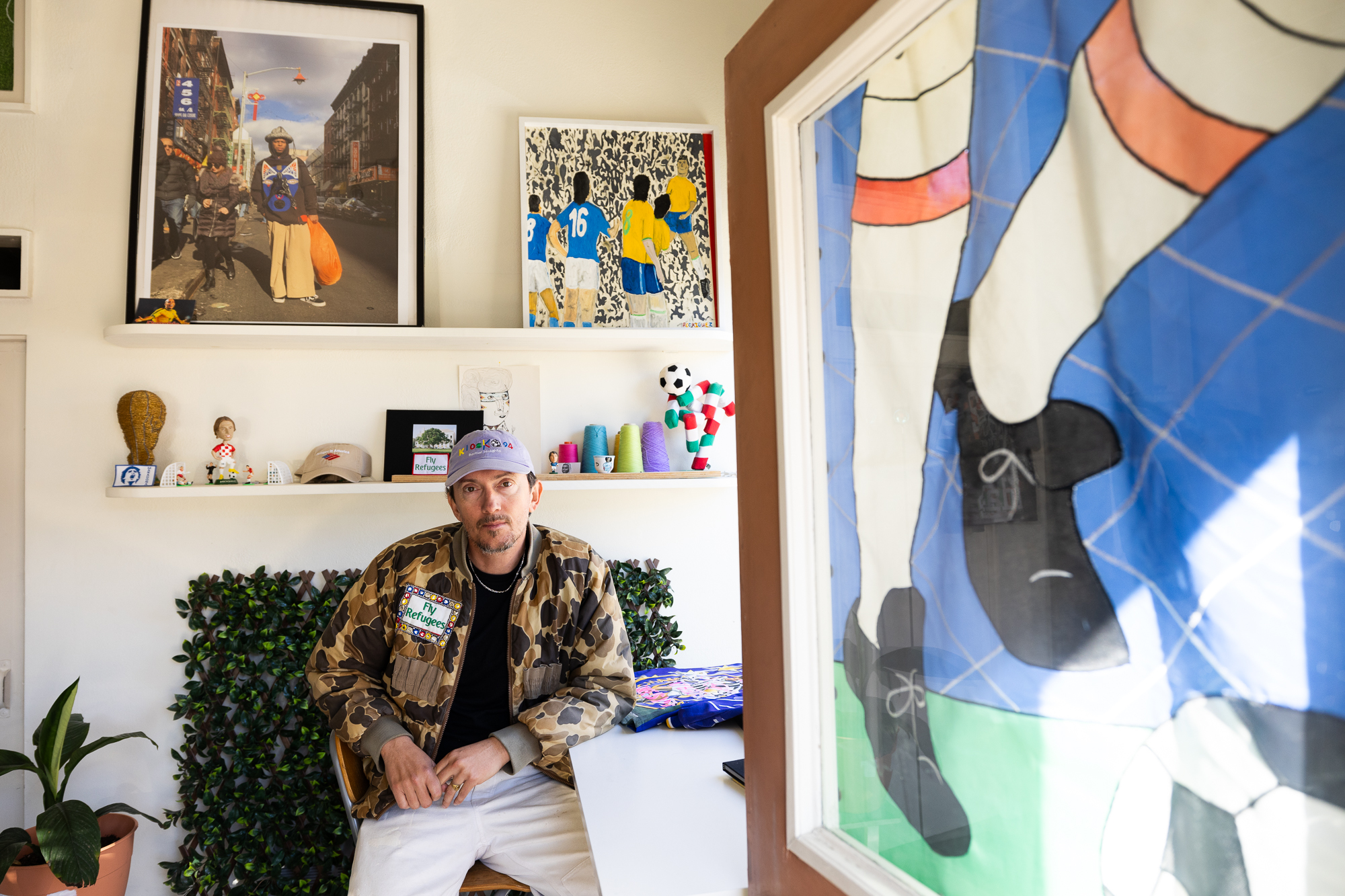 white man sitting in studio surrounded by images of athletes and textile art