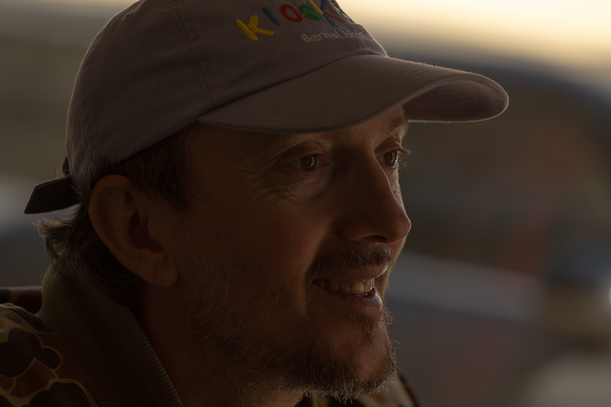 white man in baseball cap in dim light