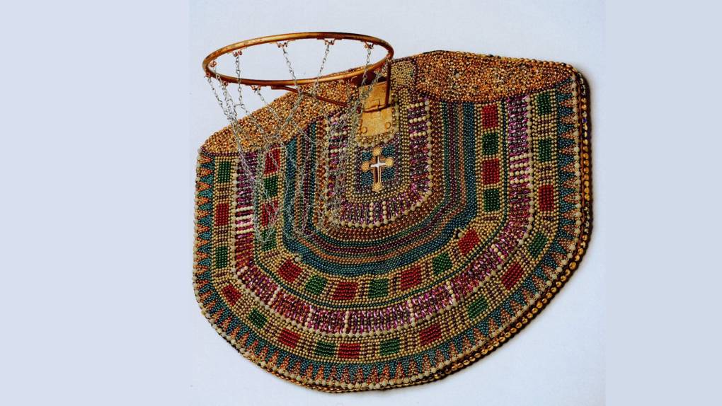 An upturned basketball hoop is covered in beads of traditional African colors.