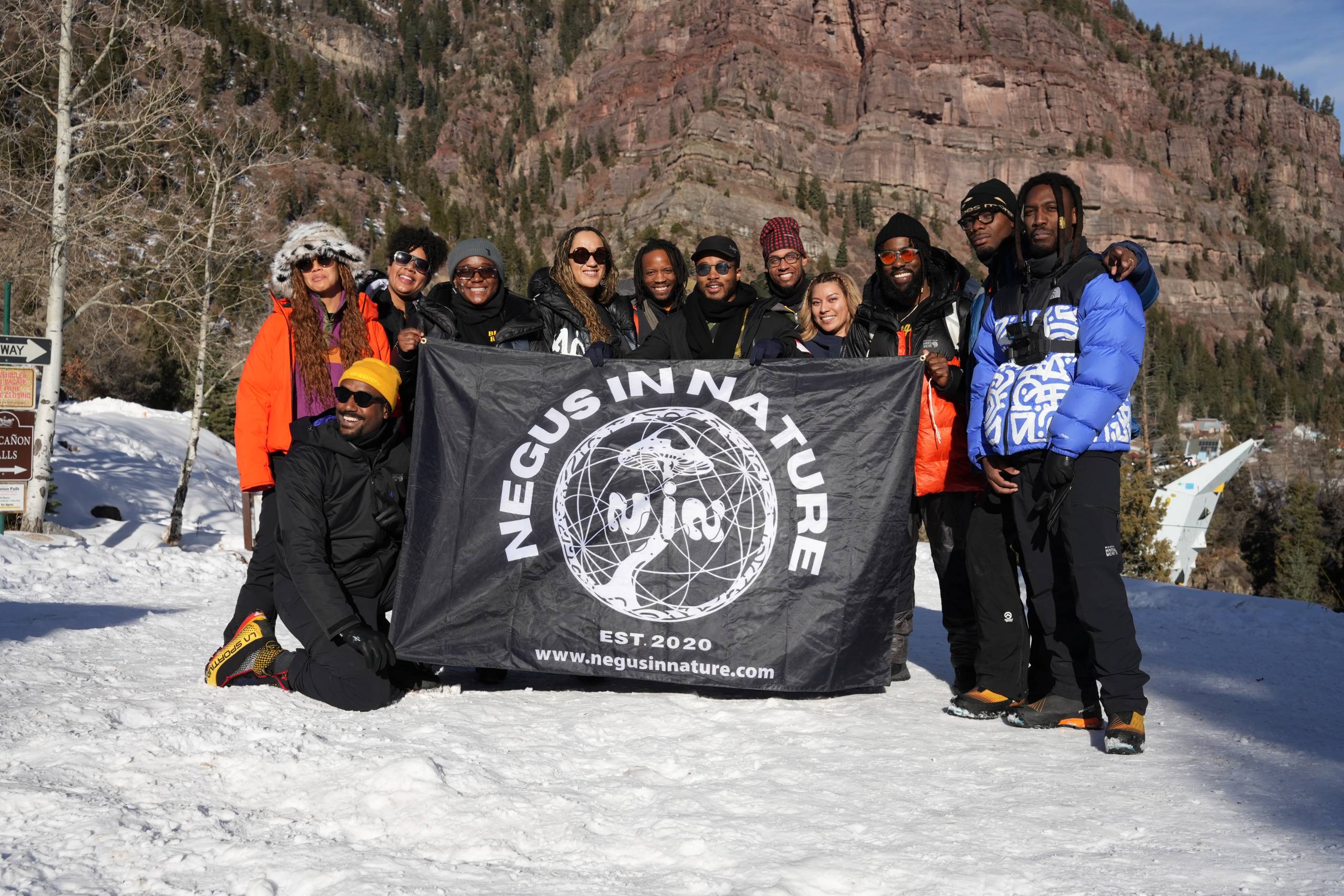 A group of people holding a 'Negus In Nature' banner while standing in snow.