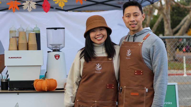 Two baristas posing for a portrait in front of an outdoor coffee stand.