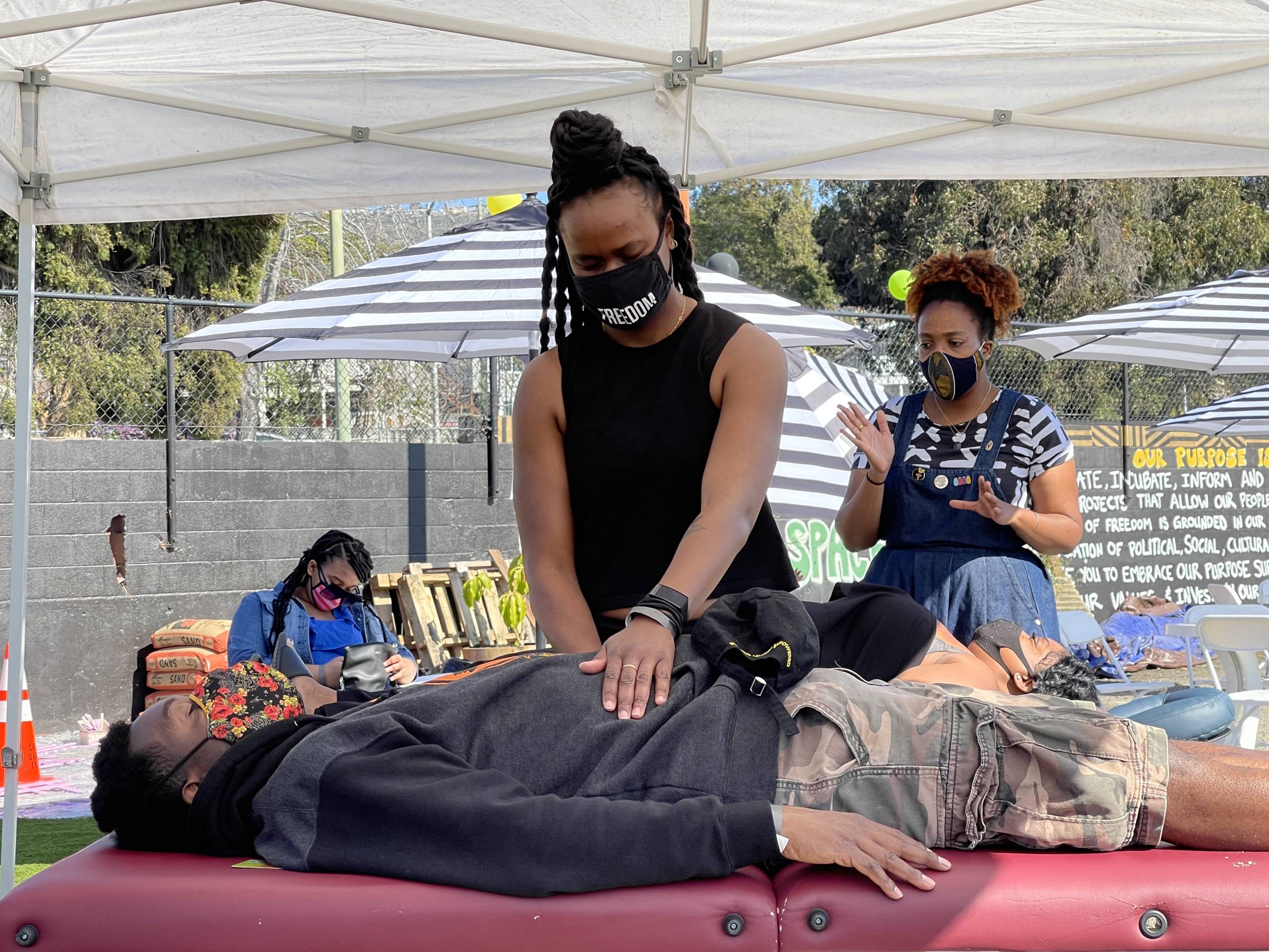 A massage therapist works on a client at a gathering at a park. 