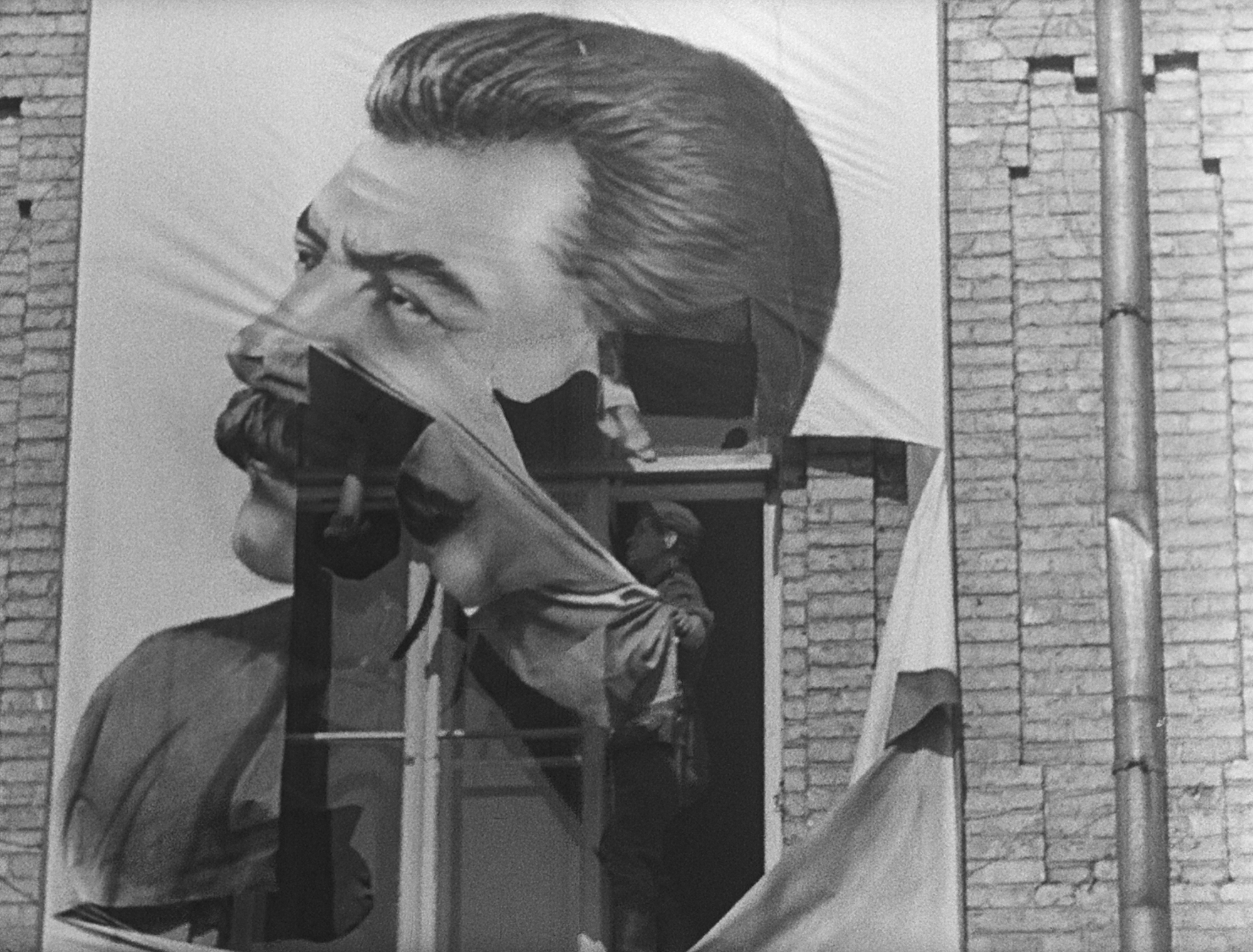 man tears down giant image of a leader