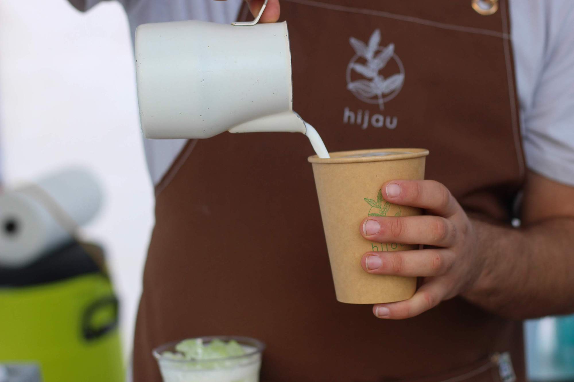 Close-up of a barista pour milk into a coffee drink.