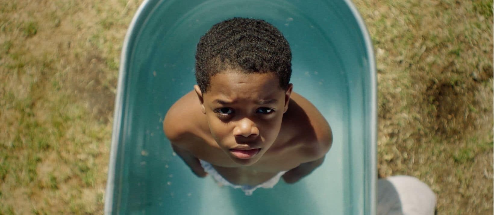 Black boy looks up in wash basin