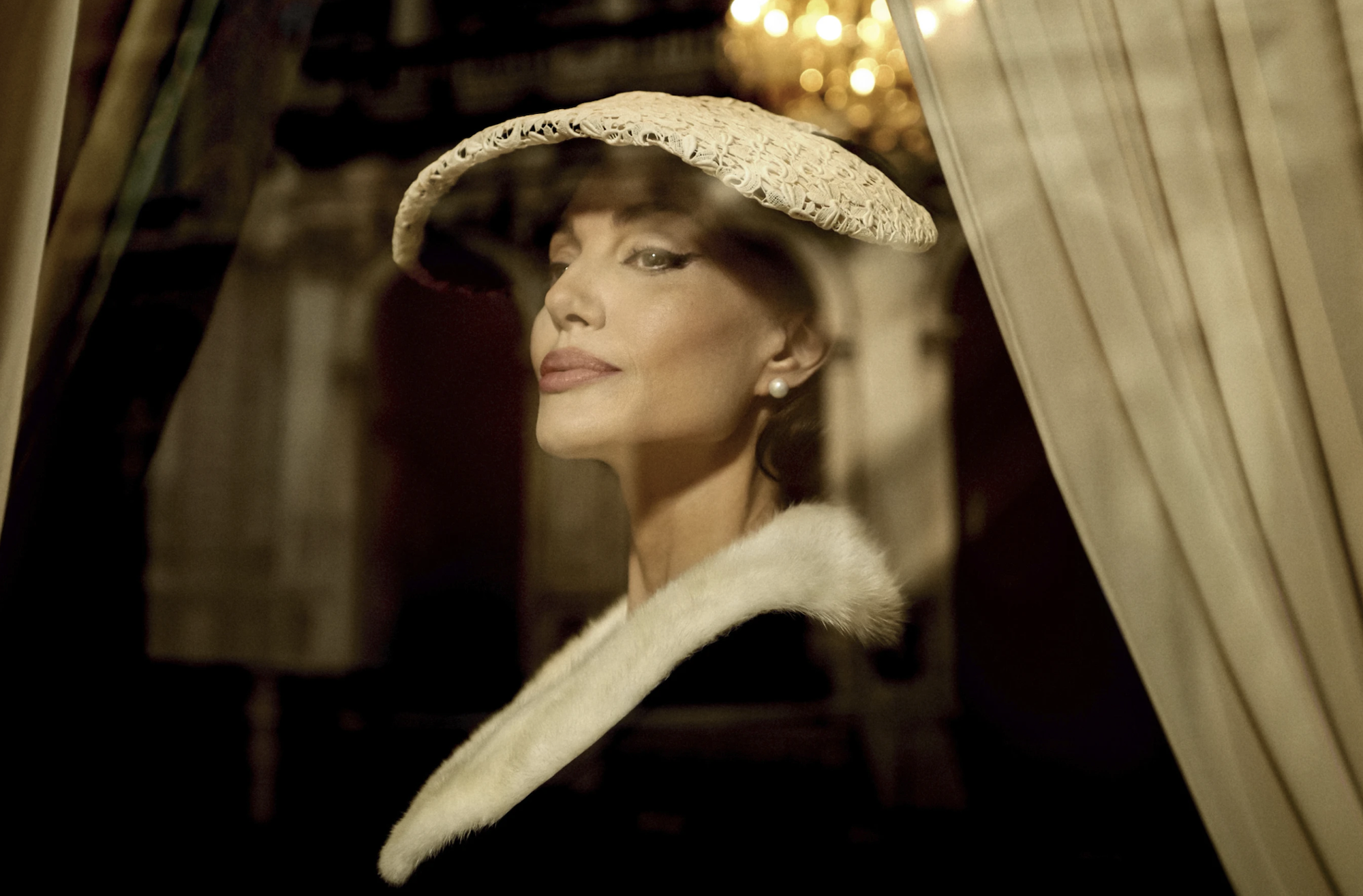 A beautiful, proud looking woman gazes out of a window.wearing a white hat and black and white gown.