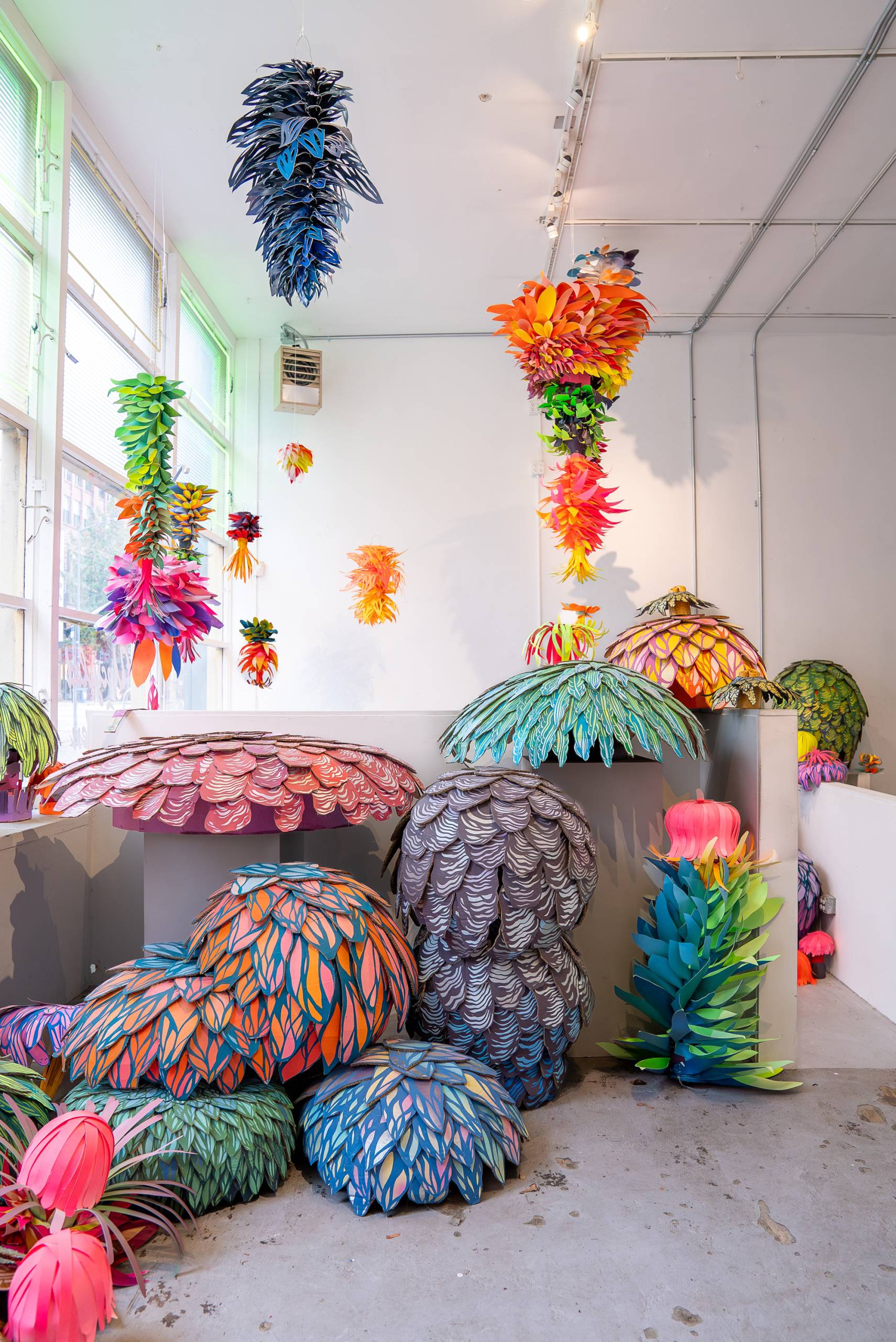 organic-looking sculptures made from painted paper on floor and hanging from ceiling