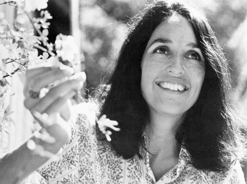 black and white photo of a woman with shoulder length brown hair smiling in the sunshine.