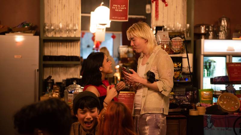 Two partygoers greet each other inside a crowded bar.