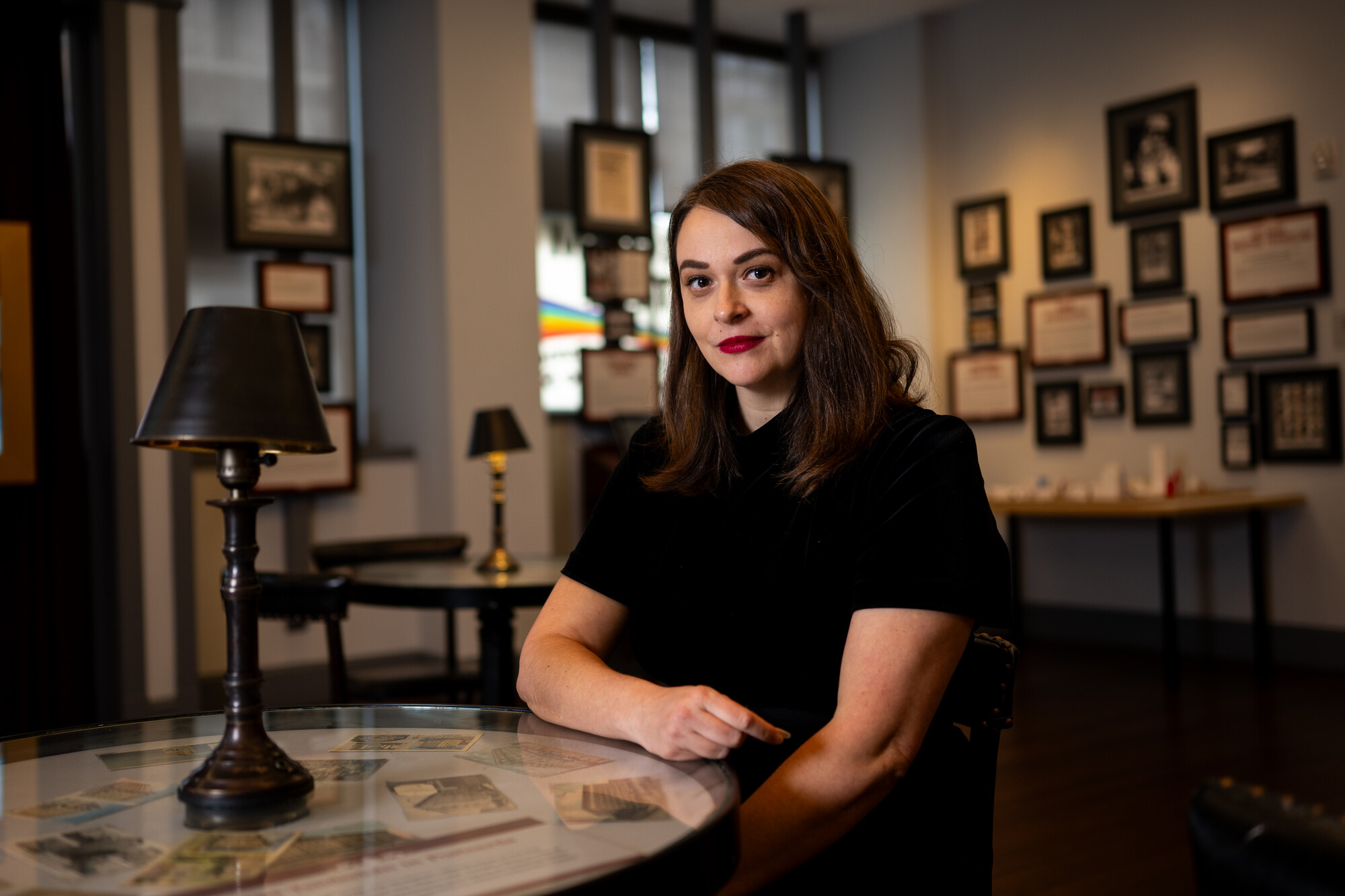 white woman in black poses at table in museum gallery