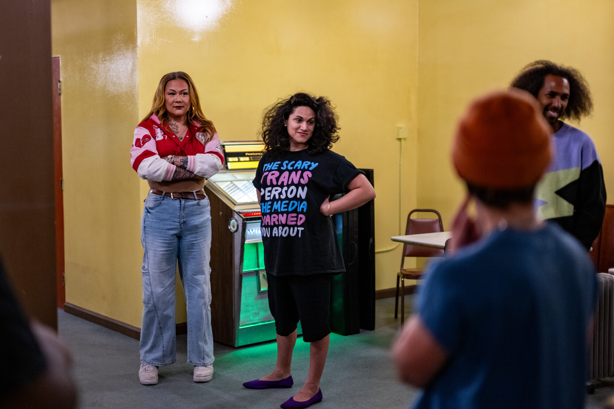 two people stand in front of jukebox looking to right
