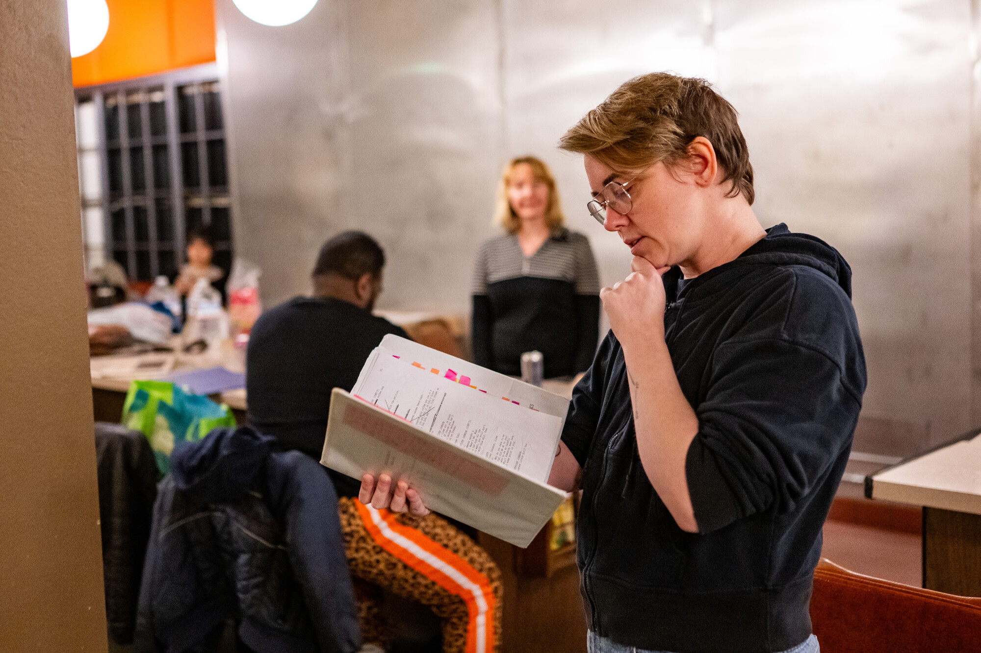 person looks at notebook of dialogue while holding chin
