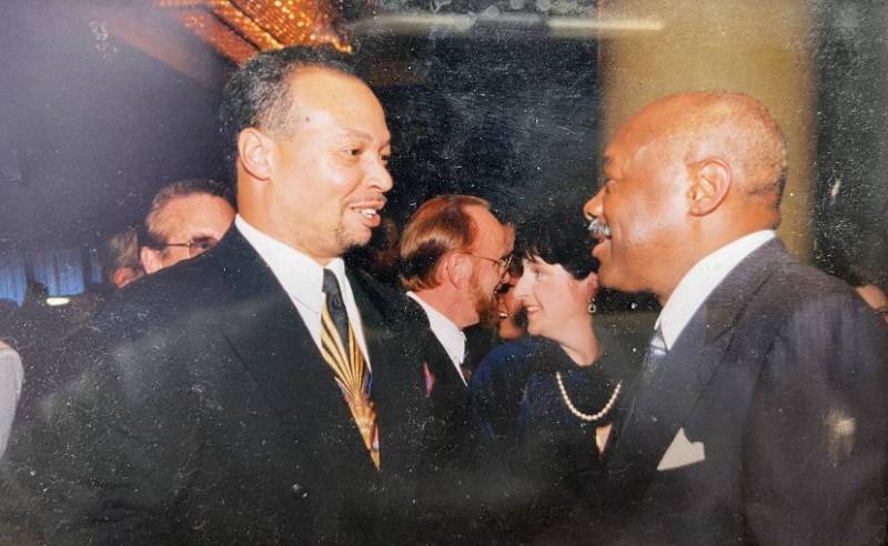 A candid photo of two men in suits engaging in conversation.