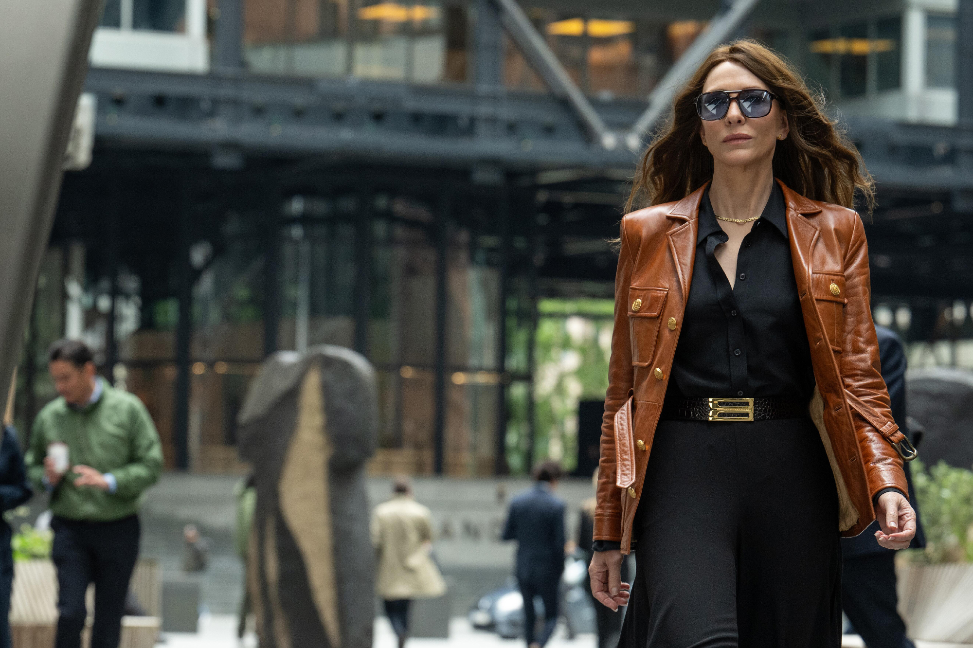 woman in sunglasses walks in front of large office building