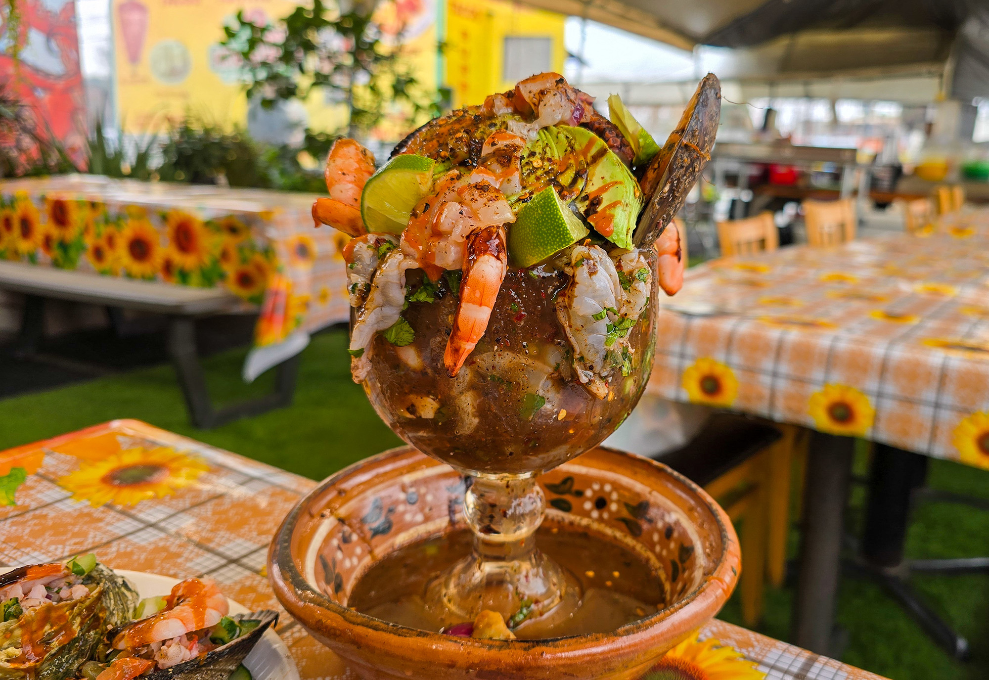 A glass chalice overflowing with shrimp and other seafood.