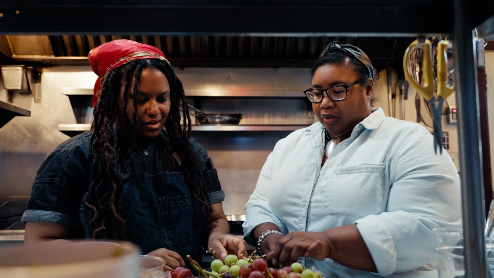 Two women prep vegetables in a restaurant kitchen.