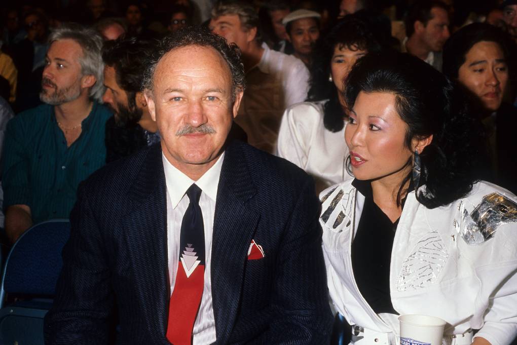 white man in suite and asian woman looking at him in seated crowd