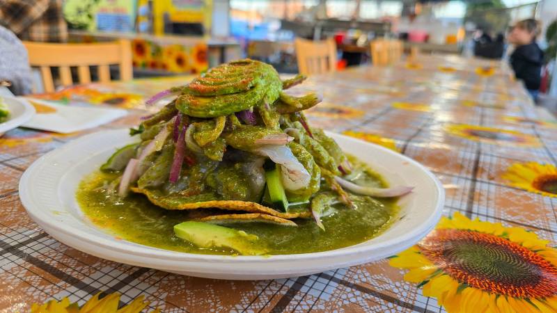 Raw shrimp, avocado and onion layered on top of a tostada and drenched in green sauce.