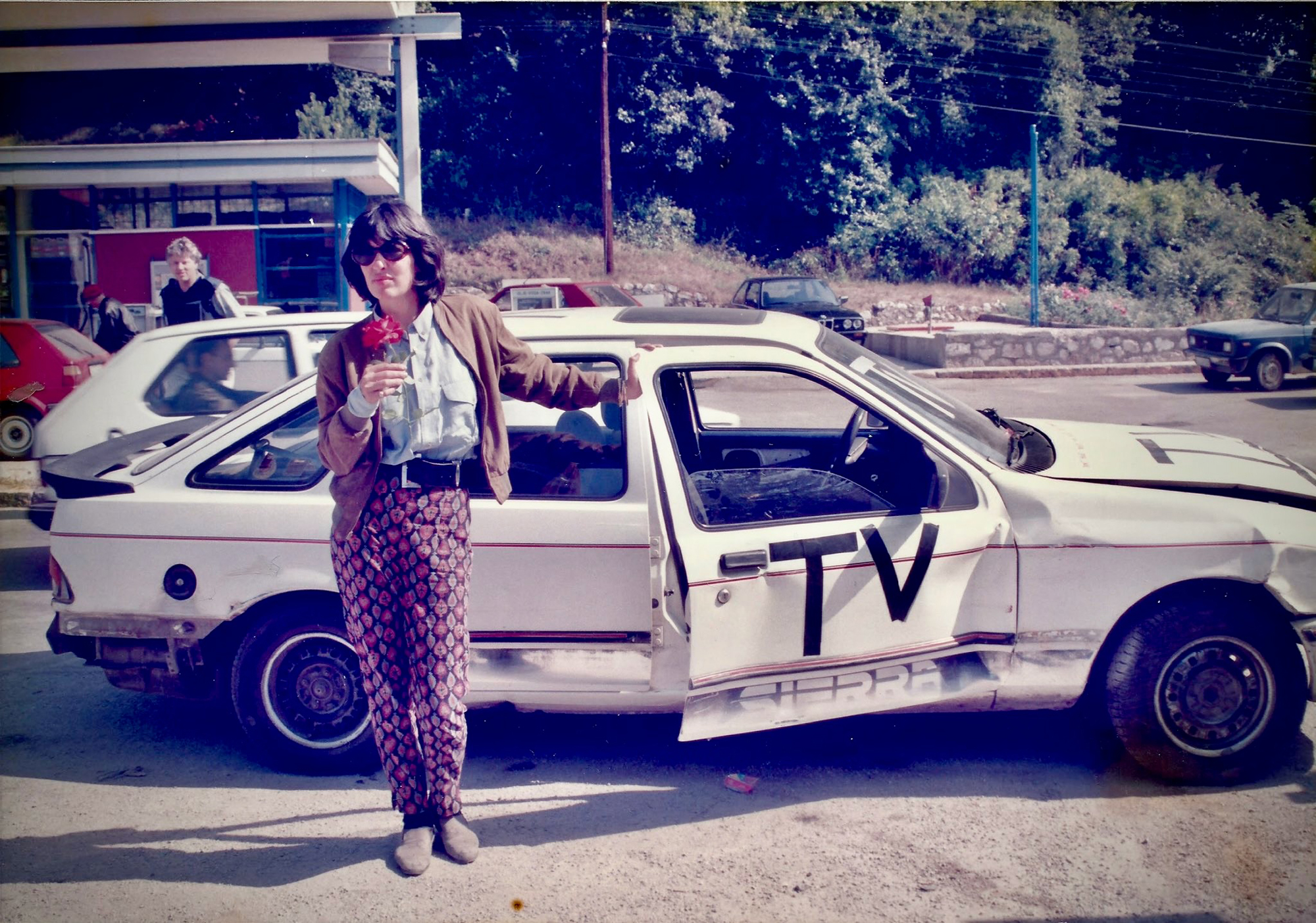 woman standing with hand on open door of car with 'TV' on side