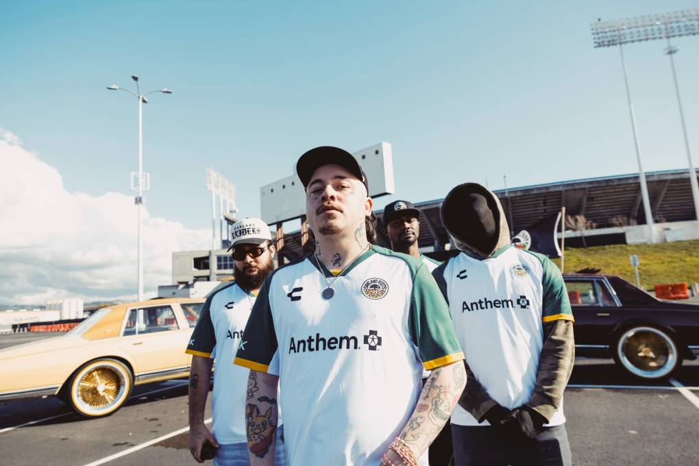 three men in soccer jerseys in parking lot outside stadium