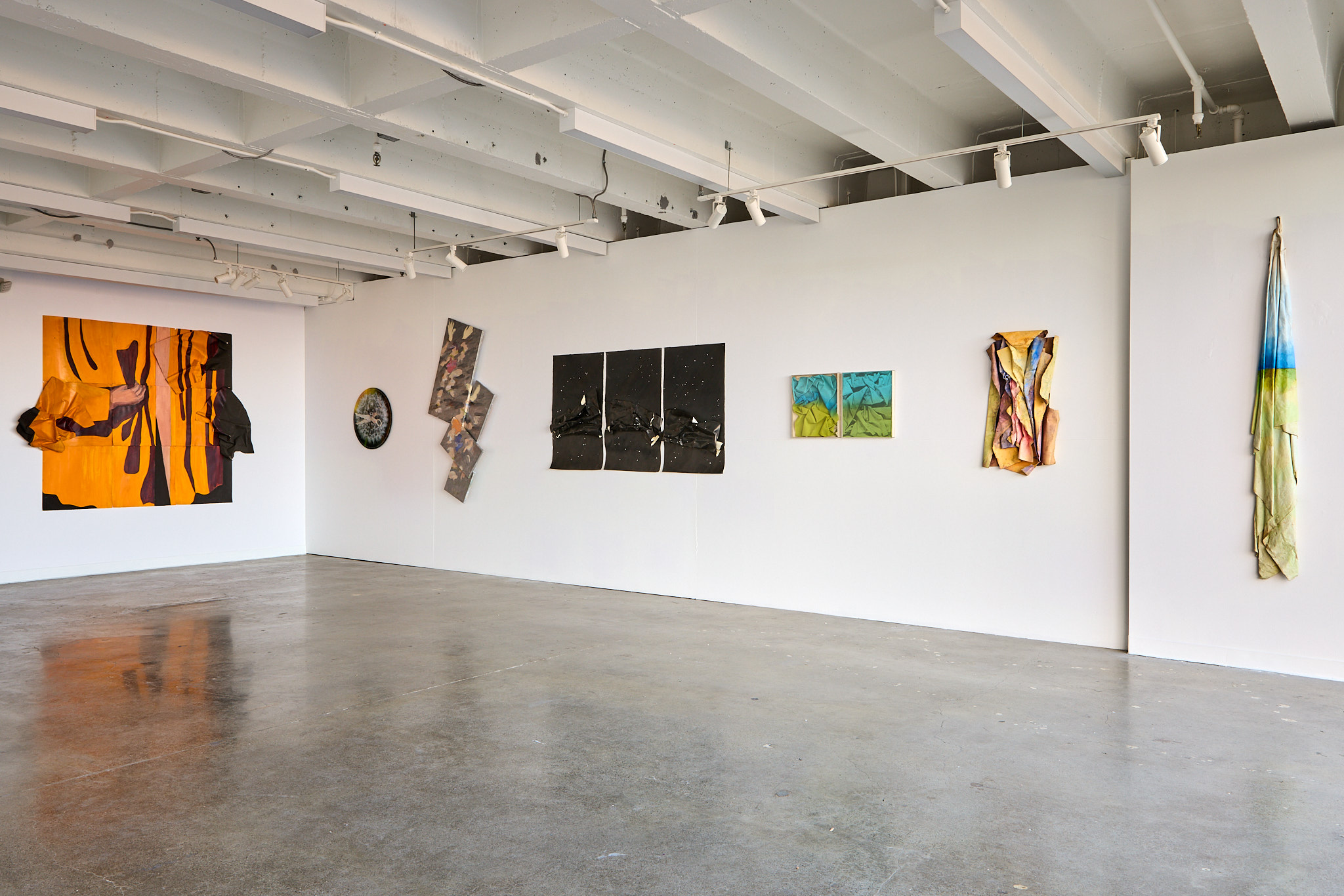 paintings and paper artworks on white walls of gallery