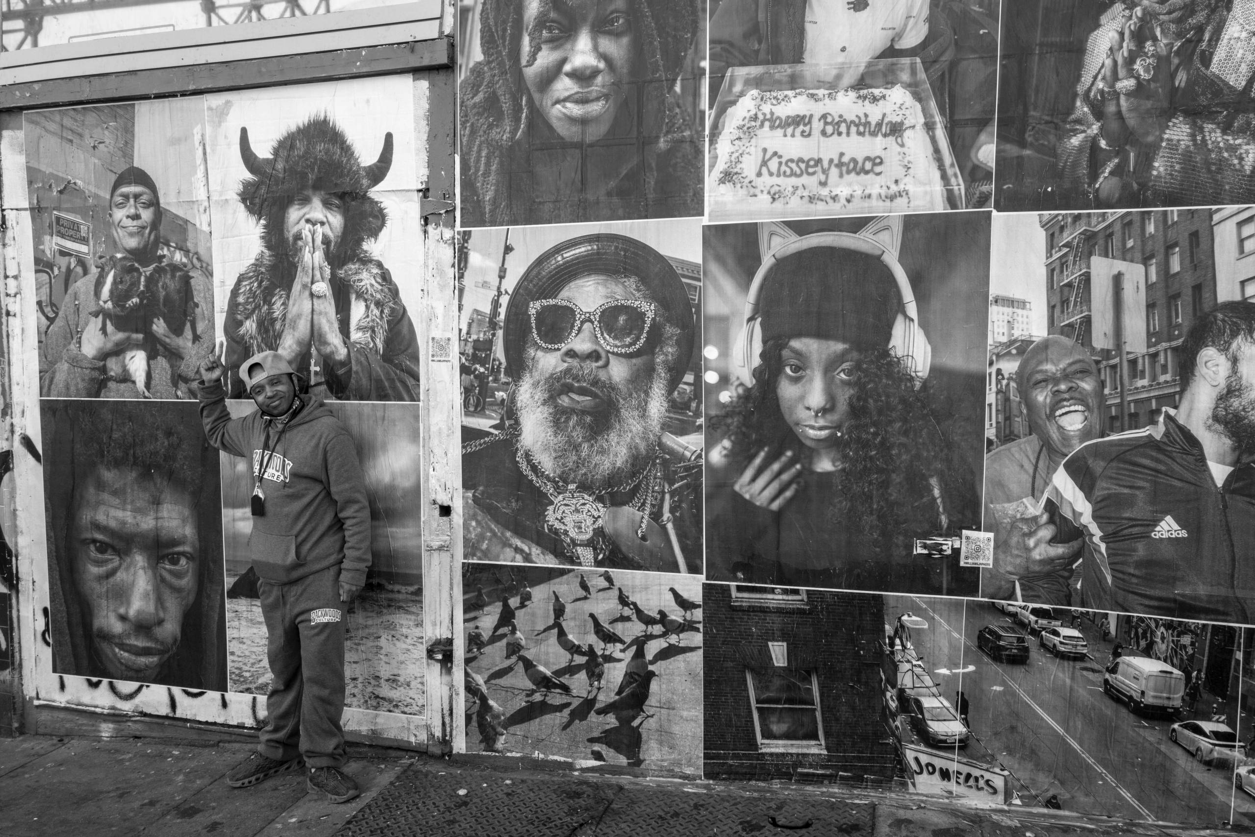 A man stands next to a wheat-paste mural of images.