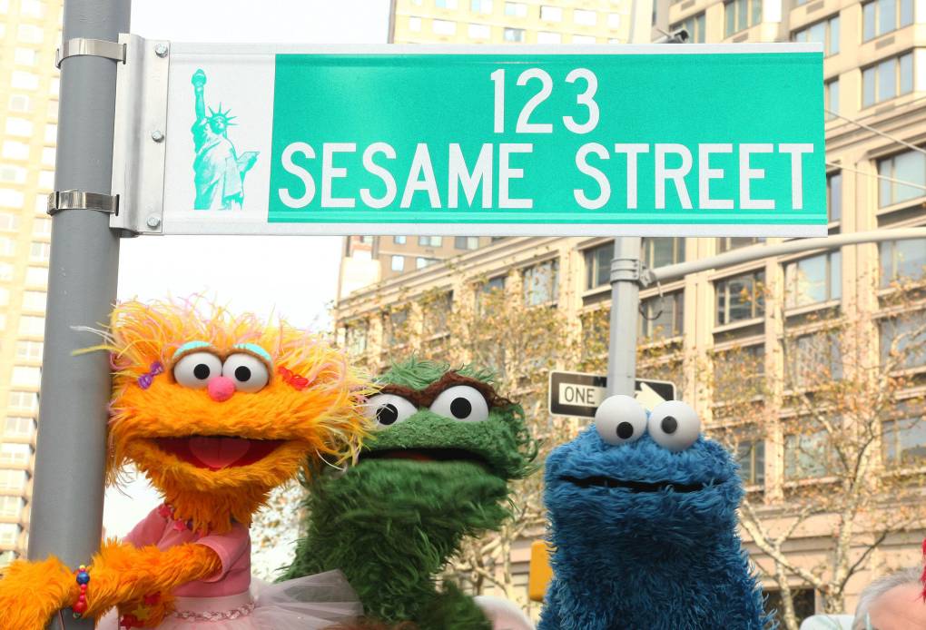 three muppets under a street sign