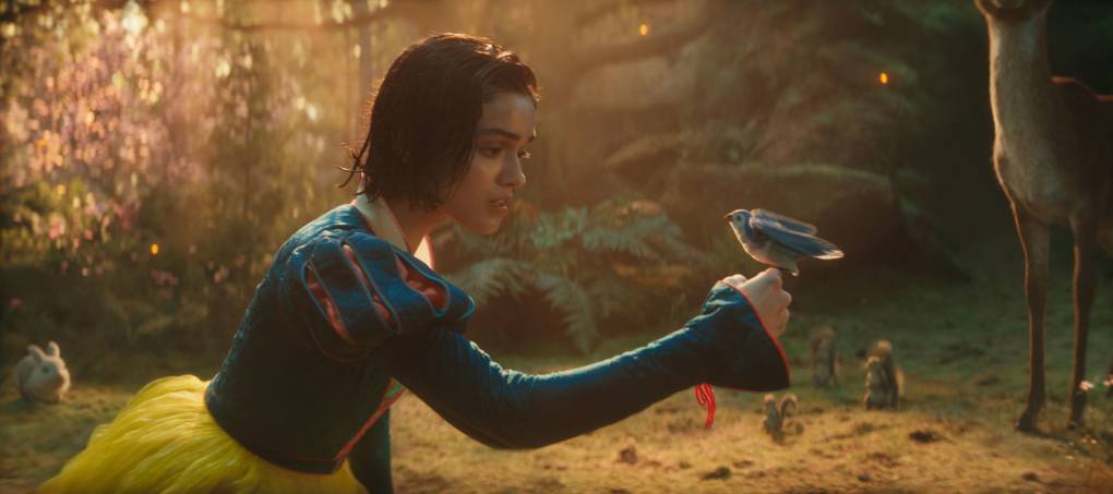 young woman in blue dress with small bird perched on her hand
